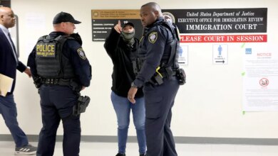 Uniformed officers converse with a plainclothes agent while monitoring a corridor inside a federal courthouse.