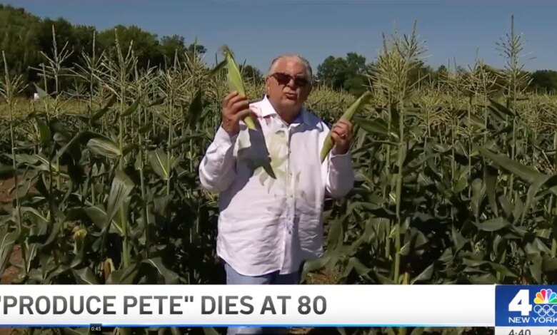 "Produce Pete" holding two ears of corn in a cornfield.