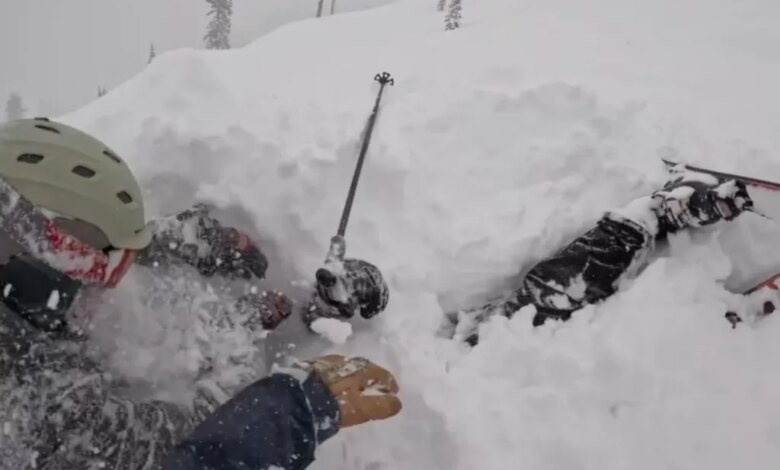 Heart stopping moment skier is rescued after being buried alive under mount of snow in Lake Tahoe 1 Three people caught in an avalanche are partially covered in snow, with a ski pole sticking out of the snow.