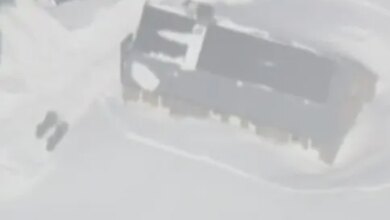 Aerial view of snow-covered buildings in Frog Lake after an avalanche.