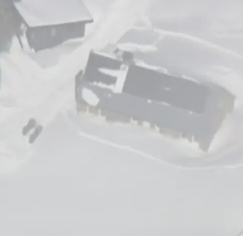 Aerial view of snow-covered buildings in Frog Lake after an avalanche.