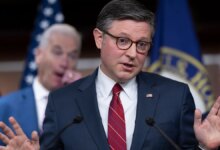 Speaker Mike Johnson gesturing with his hand while speaking to a group of reporters.