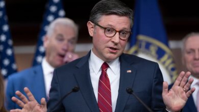 Speaker Mike Johnson gesturing with his hand while speaking to a group of reporters.