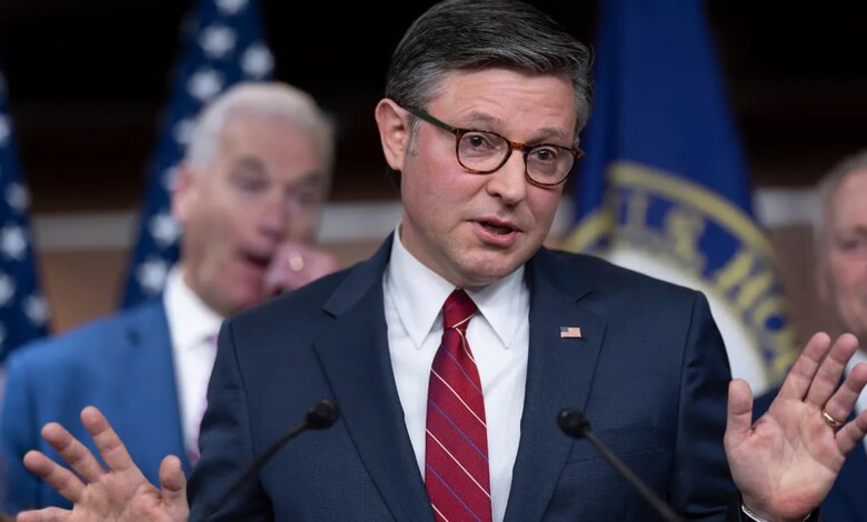 Speaker Mike Johnson gesturing with his hand while speaking to a group of reporters.