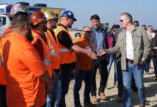 California Gov. Gavin Newsom shaking hands with an Iron Workers Local 155 worker as Ian Choudri, CEO for the California High-Speed Rail Authority, watches.