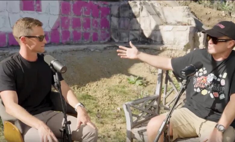 Two men in sunglasses having a discussion with microphones outdoors.