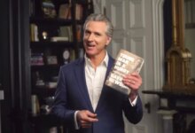 Gavin Newsom holding up his book, "Young Man in a Hurry: A Memoir of Discovery"