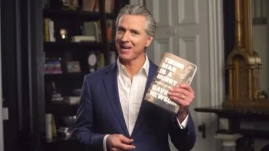 Gavin Newsom holding up his book, "Young Man in a Hurry: A Memoir of Discovery"