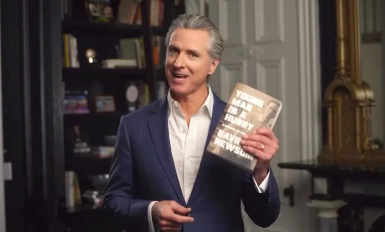 Gavin Newsom holding up his book, "Young Man in a Hurry: A Memoir of Discovery"