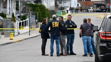 FBI agents and law enforcement gather at a crime scene blocked off by yellow police tape.