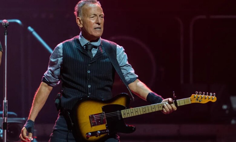 Bruce Springsteen performing on stage with a guitar.