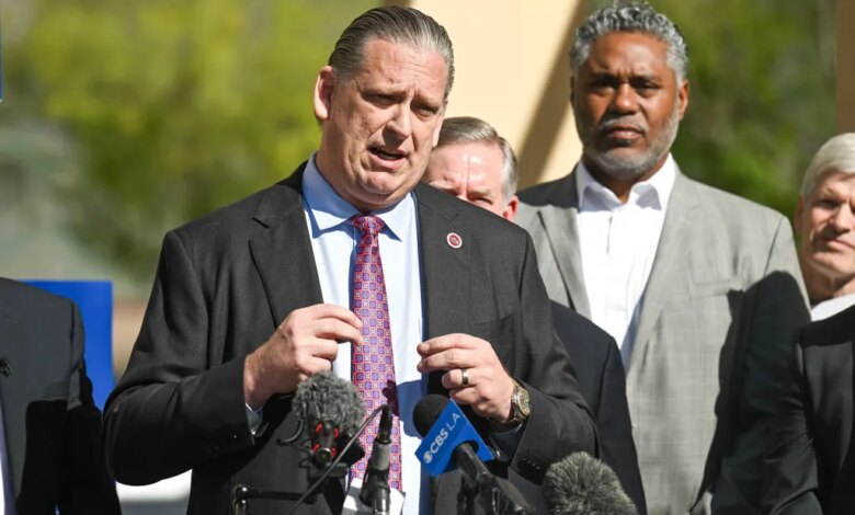 Sen. Tony Strickland speaking at a press conference with two microphones in front of him and other men behind him.