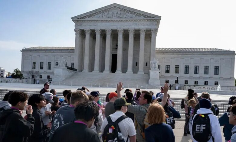 people stand in front of the Supreme Court