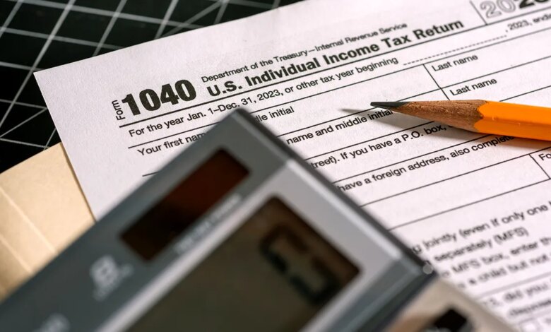 A 1040 tax form is covered by a pencil and a calculator.