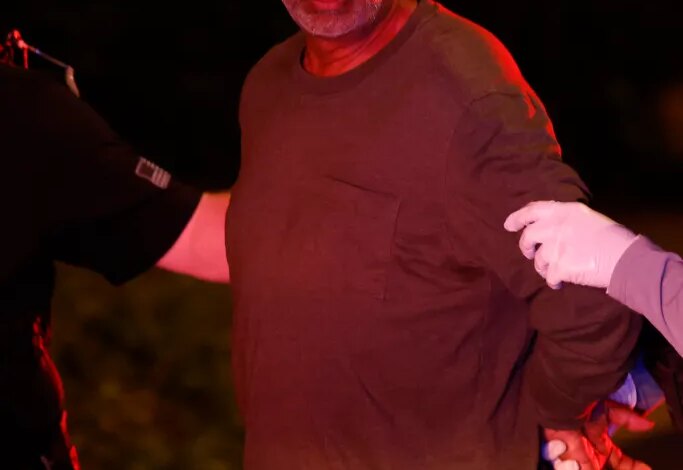 Gladwin Gill, who operates St. Francis Palliative Care in Anaheim, is apprehended by law enforcement agents.