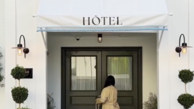 A person with a suitcase approaches the entrance of a building with an awning that says "HÔTEL".