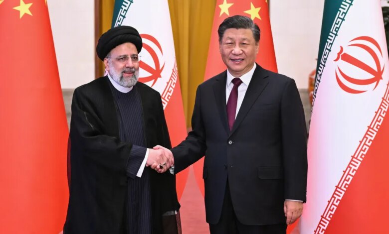 Iranian President Ebrahim Raisi and Chinese President Xi Jinping shake hands in front of their national flags.