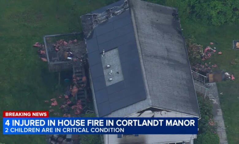 Aerial view of a house with extensive fire damage to the roof and a news overlay stating "4 INJURED IN HOUSE FIRE IN CORTLANDT MANOR, 2 CHILDREN ARE IN CRITICAL CONDITION."