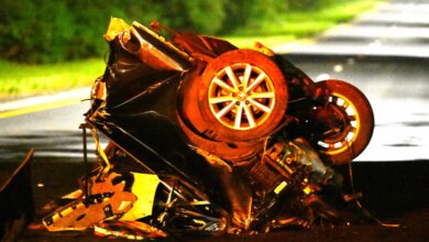 The wreckage of a car split in half on a road after a fatal accident.