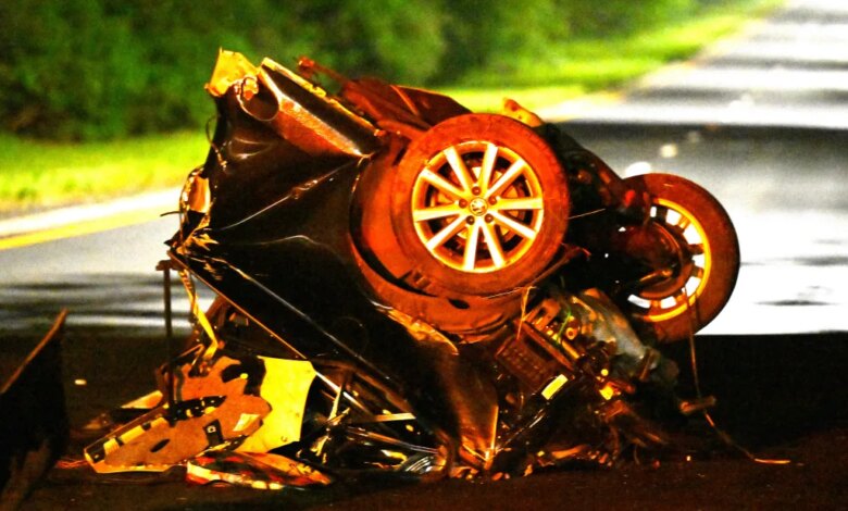 The wreckage of a car split in half on a road after a fatal accident.