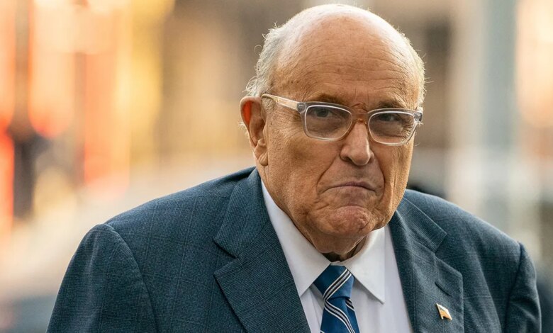 Former New York City Mayor Rudy Giuliani wearing glasses, looking serious