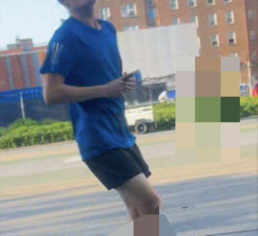 A cropped image of an individual sought by the NYPD, wearing a blue shirt and black shorts, walking on a street.