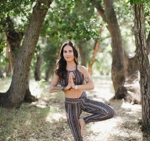 Ashley Phillips in a yoga tree pose outdoors.
