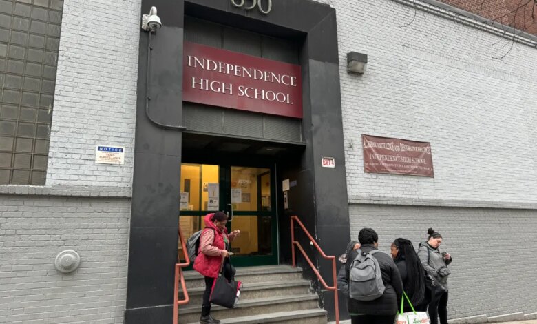 Students stand on the steps and sidewalk outside Independence High School, where a video surveillance notice is posted on the wall.