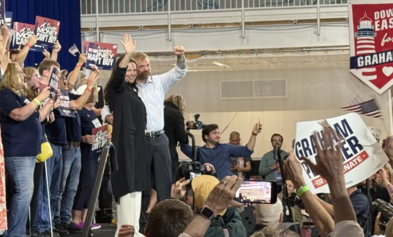 Graham Platner and wife waving on stage to supporters