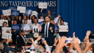 JD Vance addresses a crowd holding signs that say "Enough is Enough."