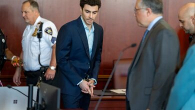 Luigi Mangione, accused of killing UnitedHealthcare CEO Brian Thompson, stands handcuffed in a courtroom.