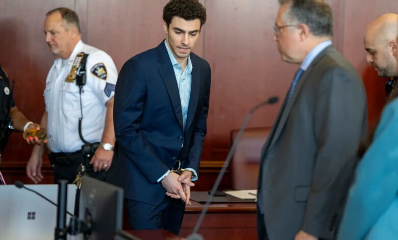 Luigi Mangione, accused of killing UnitedHealthcare CEO Brian Thompson, stands handcuffed in a courtroom.