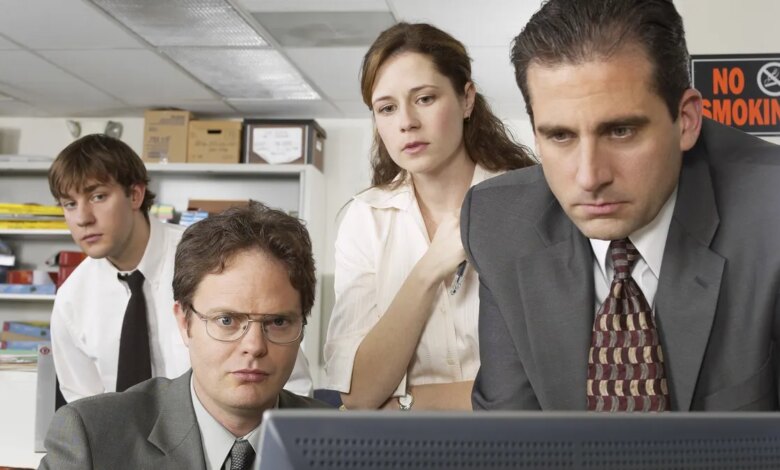 John Krasinski as Jim Halpert, Rainn Wilson as Dwight Schrute, Jenna Fischer as Pam Beesly, and Steve Carell as Michael Scott standing in an office setting