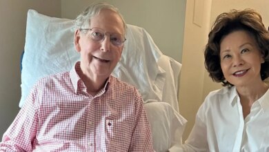 Mitch McConnell sits from a hospital chair next to his wife.
