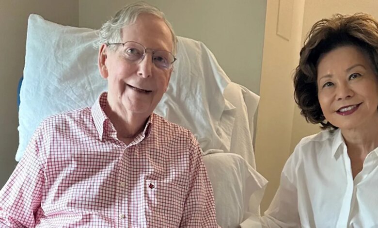 Mitch McConnell sits from a hospital chair next to his wife.