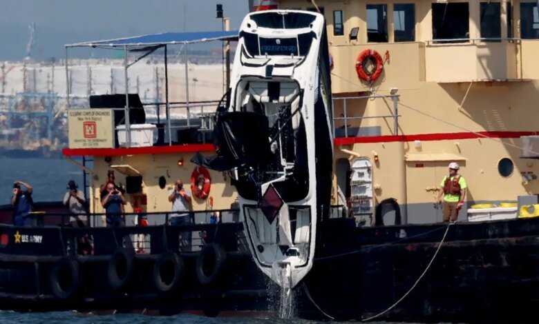 An overturned bowrider motorboat is lifted from the water by a crane vessel.