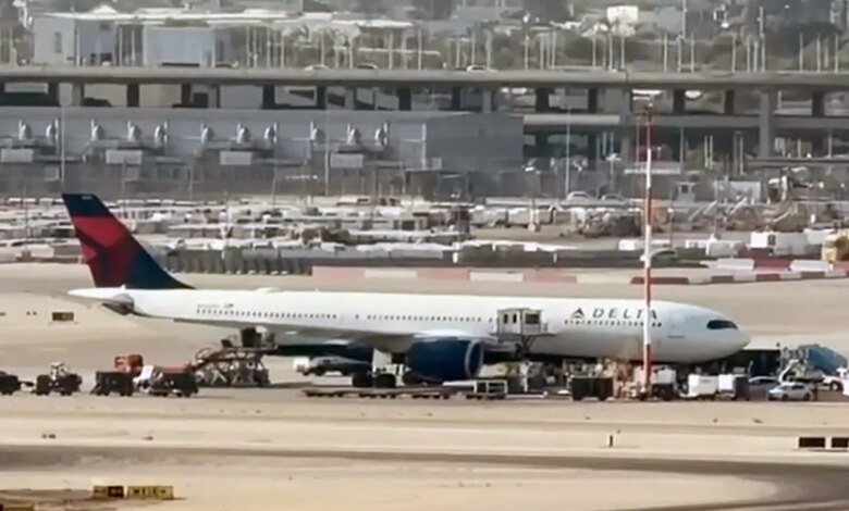A Delta Air Lines passenger plane parked at an airport tarmac, surrounded by service vehicles.