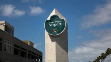 John Wayne Airport sign under a blue sky.