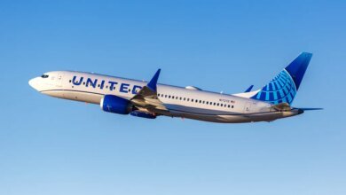 United Boeing 737 MAX 8 airplane taking off against a clear blue sky.